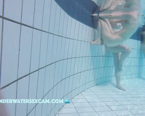 A really pretty naked girl holds on to the edge of the pool and is being filmed underwater with a hidden camera.