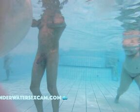 A pretty young woman with sweet tits and a huge cock filmed underwater in a public swimming pool with a spy camera