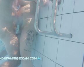 NEW! While she masturbates with the underwater jet from behind, he rubs her pierced clitoris with his hard dick